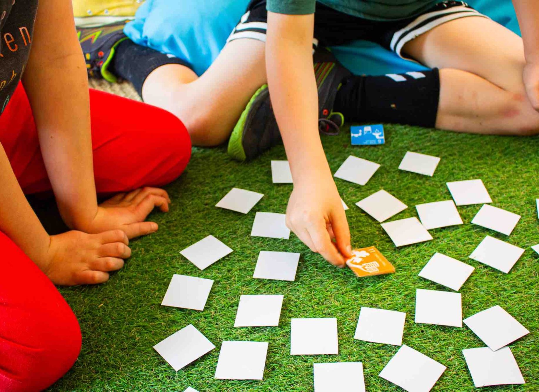 Memory-Spiel Kinder sitzen auf dem Boden und spielen ein Memory-Spiel mit Karten.